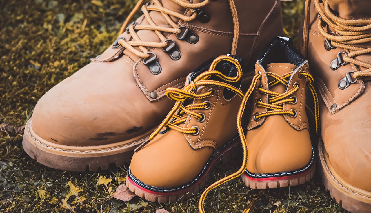 Tan leather adult and child boots on grassy background, symbolic of family and togetherness.